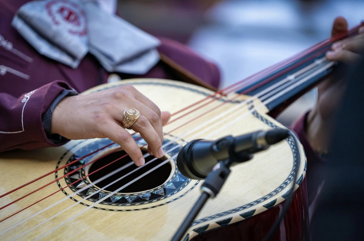 Close up of Aggieland Mariachi student playing guitar and an emphasis on his Aggie Ring